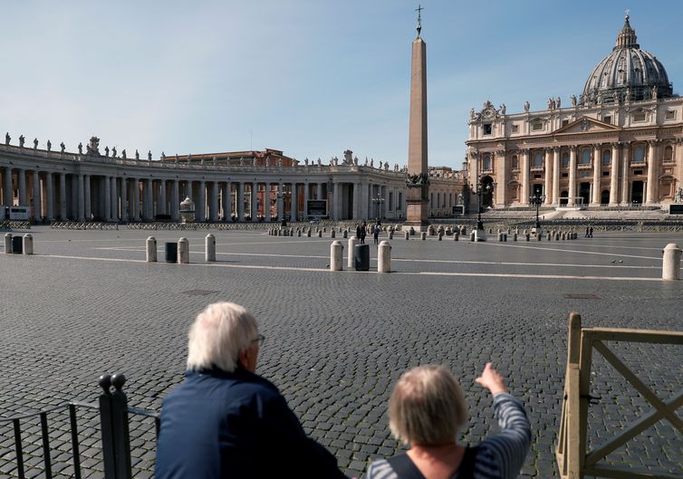 A couple look at deserted St. Peter's Square after a decree orders for the whole of Italy to be on lockdown in an unprecedented clampdown aimed at beating the coronavirus, in Rome